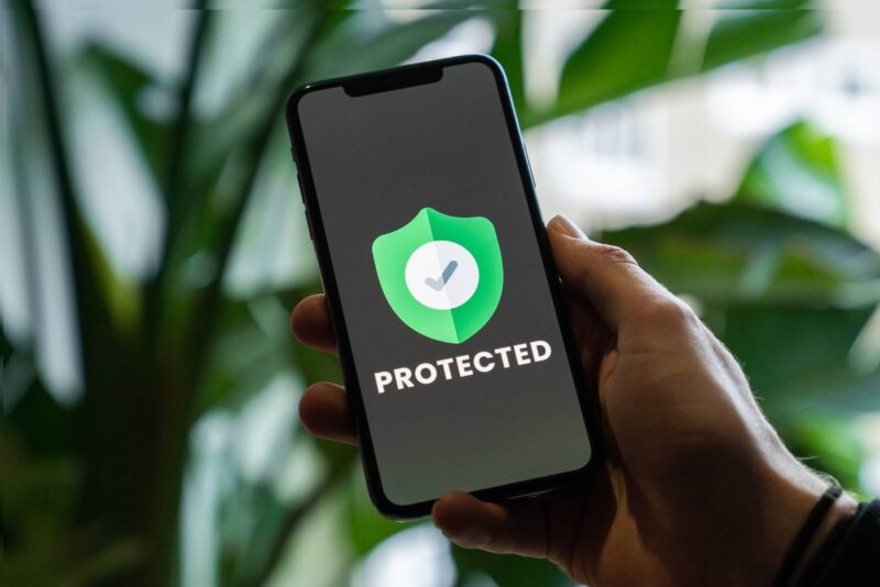 A person holding up a phone with the word protected on it.