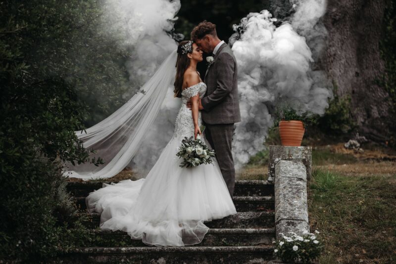 A bride and groom standing on steps with smoke coming out of their hair.