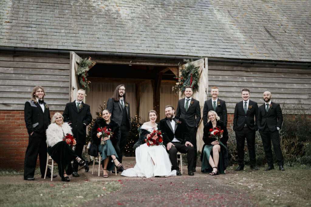 A wedding party posing in front of a barn.