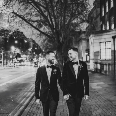 Two grooms walking down the street at night.