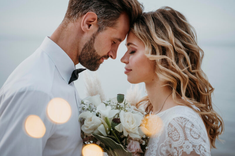 A bride and groom looking at each other at the beach.